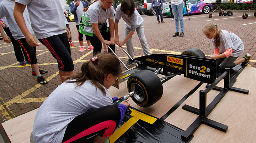 children changing wheels on a mock racing car